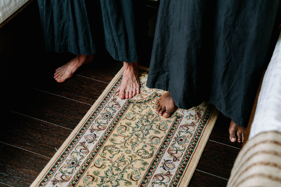 Two individuals standing with bare feet on an elegant patterned carpet indoors